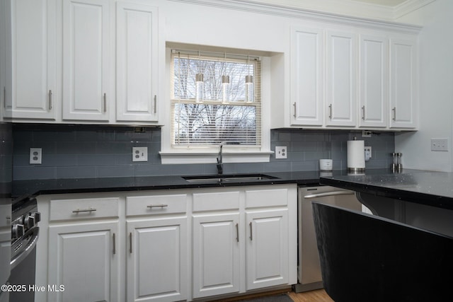 kitchen featuring decorative backsplash, gas range, a sink, white cabinetry, and stainless steel dishwasher