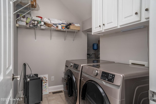 clothes washing area featuring washer and clothes dryer, light tile patterned floors, visible vents, cabinet space, and baseboards