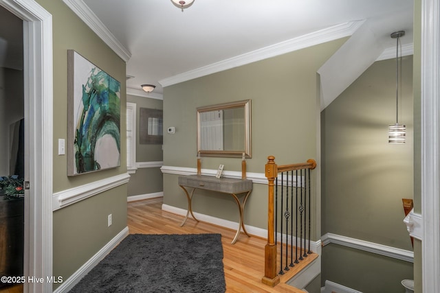 hall with crown molding, baseboards, wood finished floors, and an upstairs landing