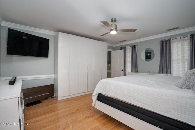 bedroom featuring light wood-style floors, visible vents, a ceiling fan, and ornamental molding