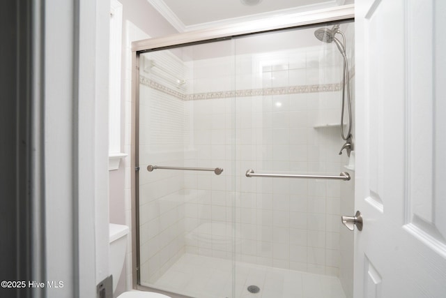 bathroom with toilet, a stall shower, and ornamental molding