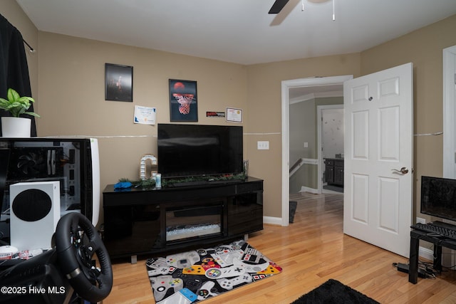 living area with light wood-style floors, ceiling fan, and baseboards