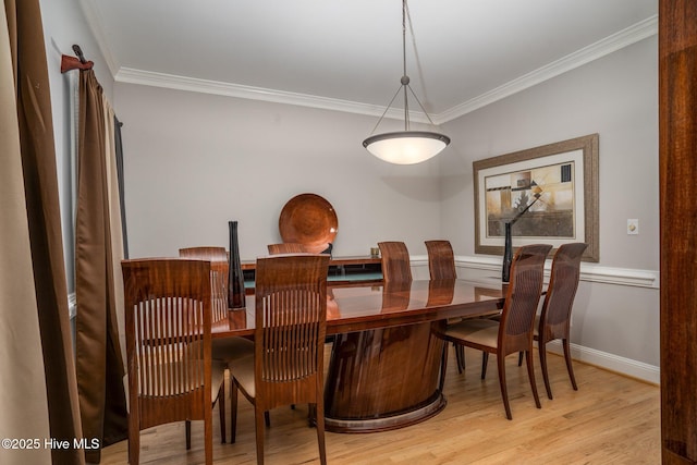 dining room with ornamental molding, baseboards, and light wood finished floors