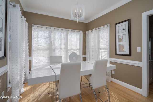 dining space with baseboards, ornamental molding, a chandelier, and wood finished floors