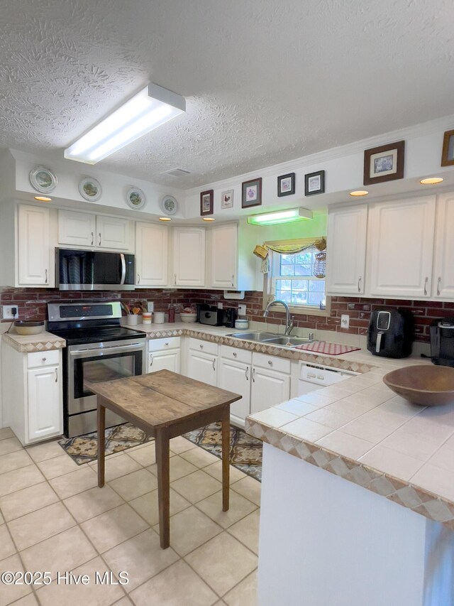 kitchen featuring visible vents, a sink, a peninsula, white cabinets, and decorative backsplash