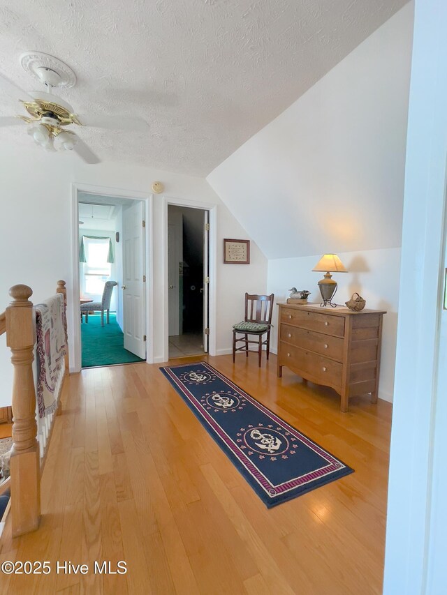 interior space featuring vaulted ceiling, a textured ceiling, and wood finished floors