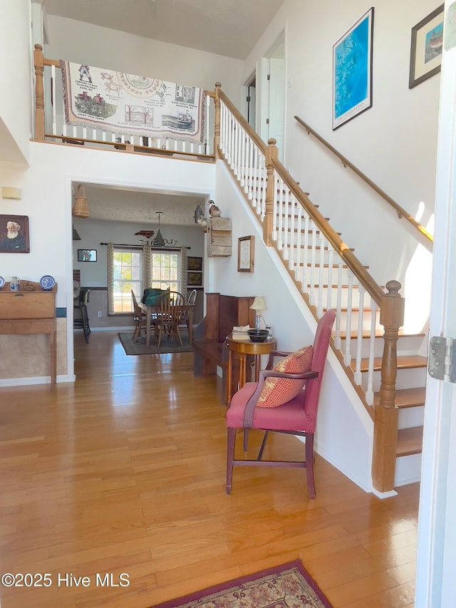 stairs featuring baseboards, a towering ceiling, and wood finished floors