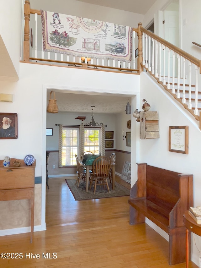 dining area with stairway, a high ceiling, wood finished floors, and baseboards