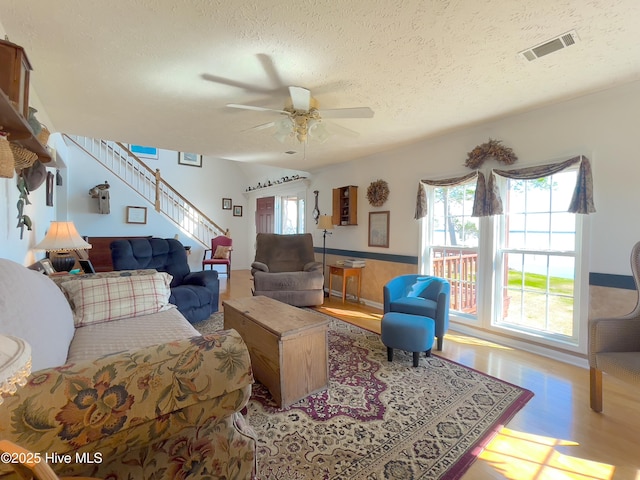 living area with a textured ceiling, plenty of natural light, visible vents, and wainscoting