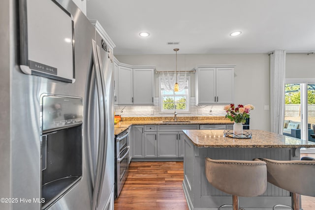 kitchen with a center island, a breakfast bar area, stainless steel appliances, backsplash, and a sink