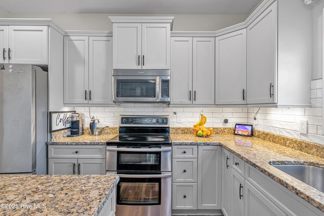 kitchen featuring stainless steel appliances, light stone countertops, and tasteful backsplash