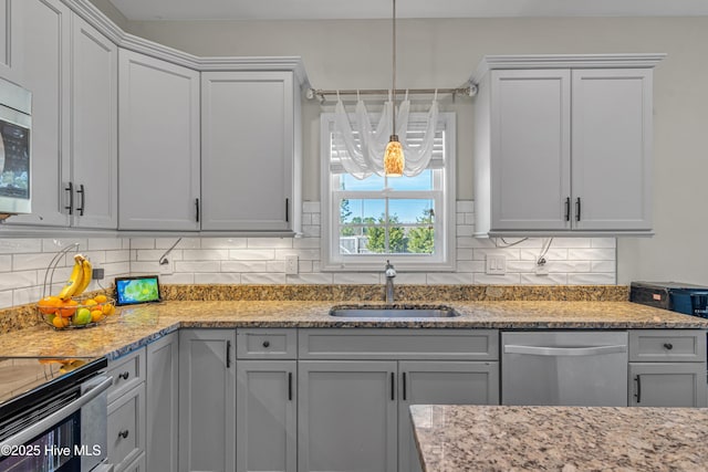 kitchen featuring light stone counters, decorative light fixtures, tasteful backsplash, stainless steel dishwasher, and a sink