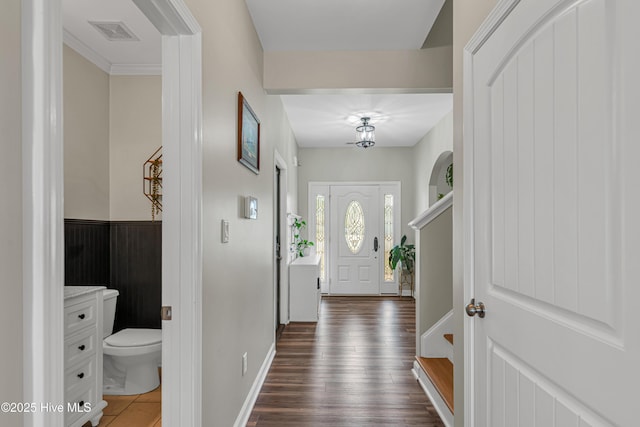 foyer entrance with dark wood-style floors, wainscoting, and visible vents