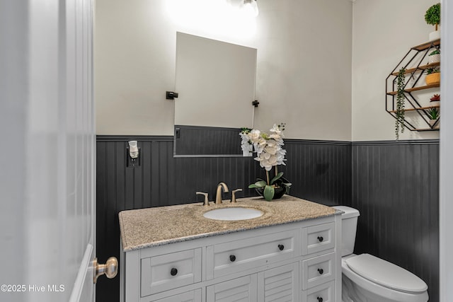 half bath featuring wainscoting, vanity, and toilet