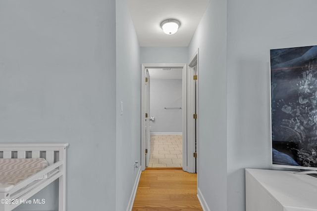 hall with light wood-style floors and baseboards