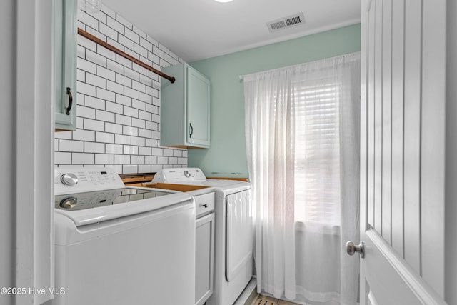 laundry area featuring separate washer and dryer, cabinet space, and visible vents