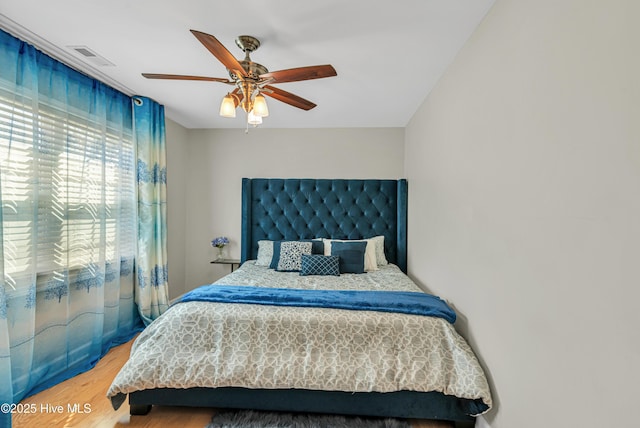 bedroom featuring ceiling fan, wood finished floors, and visible vents