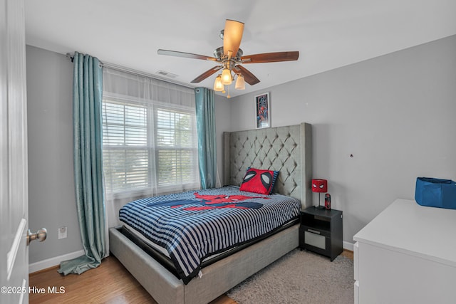 bedroom featuring light wood finished floors, a ceiling fan, visible vents, and baseboards