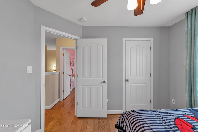 bedroom featuring ceiling fan, light wood-style flooring, and baseboards