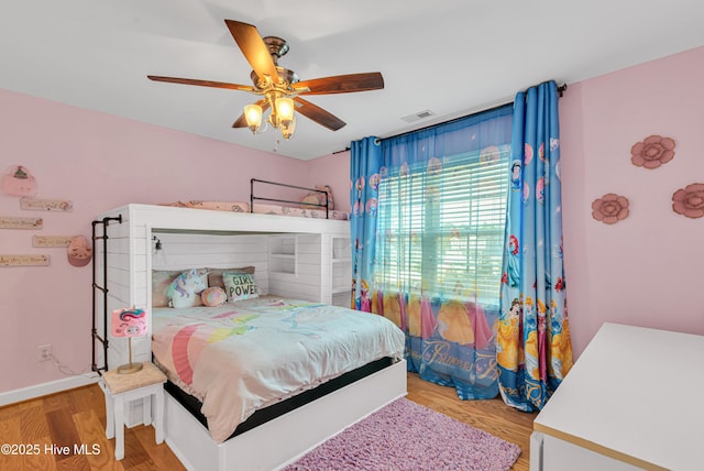 bedroom with a ceiling fan, baseboards, visible vents, and wood finished floors