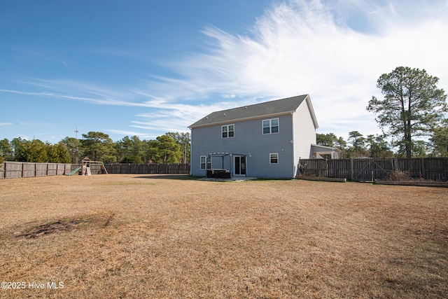 rear view of house featuring a playground, a yard, and a fenced backyard