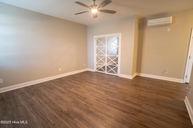 spare room featuring ceiling fan, dark wood-type flooring, a wall mounted air conditioner, and baseboards