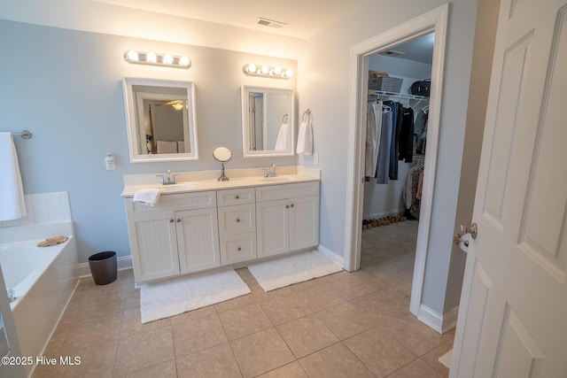 bathroom featuring a bath, double vanity, a sink, and visible vents