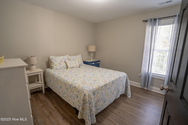 bedroom featuring dark wood-style floors, baseboards, multiple windows, and visible vents