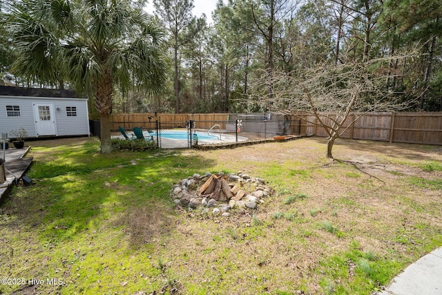 view of yard featuring a fenced in pool, an outbuilding, a fenced backyard, and a fire pit