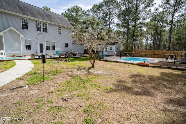 view of yard featuring a fenced in pool, fence, an outdoor structure, and a patio