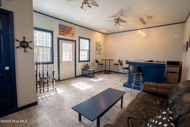 living area with visible vents, a dry bar, and a ceiling fan