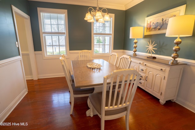 dining area with crown molding, dark wood finished floors, a notable chandelier, and wainscoting