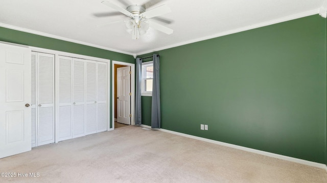 unfurnished bedroom with a ceiling fan, carpet flooring, crown molding, and baseboards