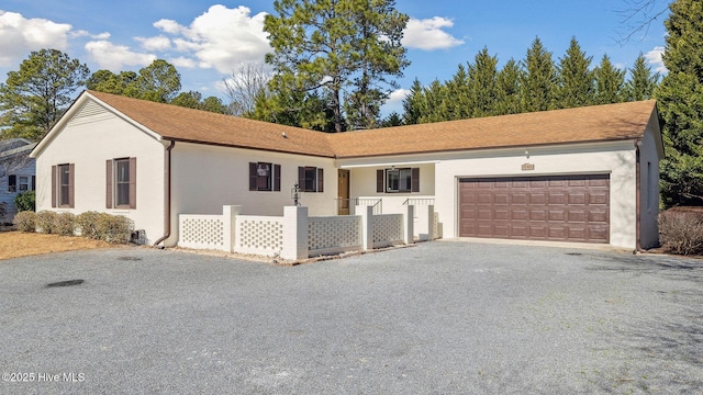 ranch-style home with driveway, an attached garage, and fence