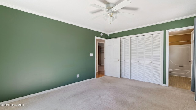 unfurnished bedroom featuring baseboards, carpet floors, ensuite bathroom, and crown molding