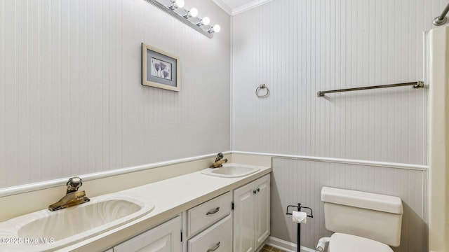 bathroom featuring toilet, crown molding, double vanity, and a sink