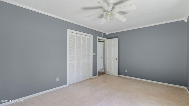 unfurnished bedroom with baseboards, a ceiling fan, ornamental molding, carpet, and a closet