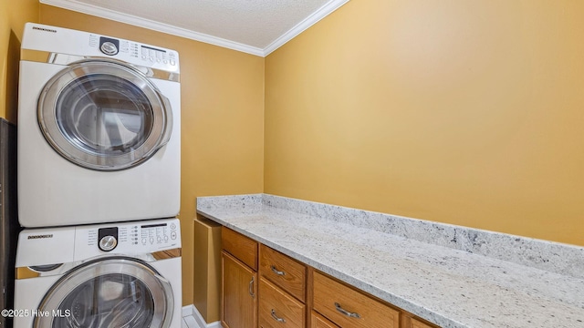 laundry area featuring a textured ceiling, stacked washer and dryer, ornamental molding, and cabinet space