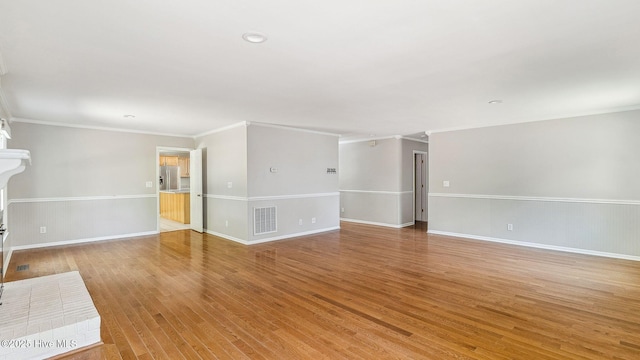 unfurnished living room with ornamental molding, visible vents, light wood-style flooring, and baseboards