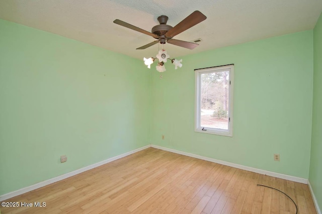 empty room featuring visible vents, ceiling fan, baseboards, and wood finished floors