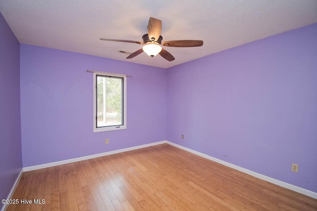 unfurnished room featuring hardwood / wood-style flooring, a ceiling fan, baseboards, and a textured ceiling