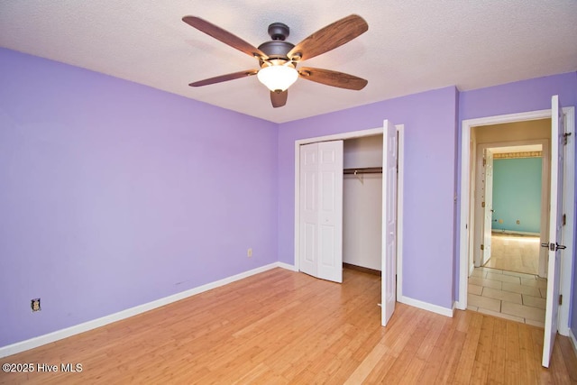 unfurnished bedroom featuring light wood-style floors, baseboards, and a textured ceiling