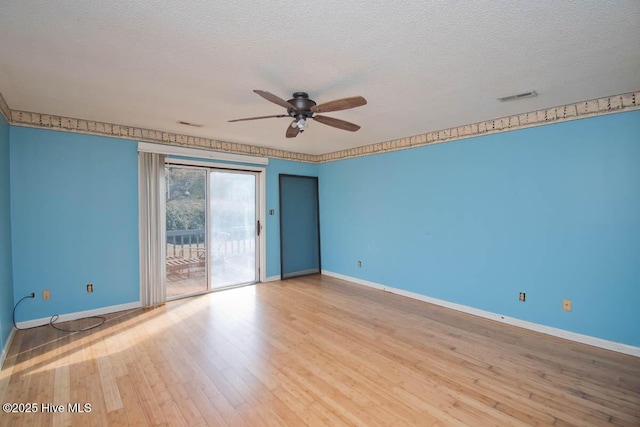 unfurnished room with visible vents, baseboards, wood finished floors, a textured ceiling, and a ceiling fan