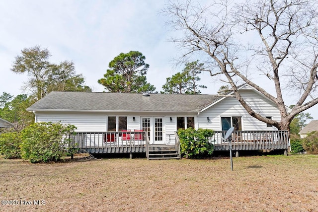 back of property featuring a lawn, a shingled roof, and a deck