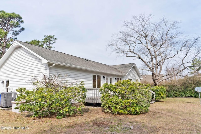 view of property exterior with central air condition unit, roof with shingles, and a wooden deck