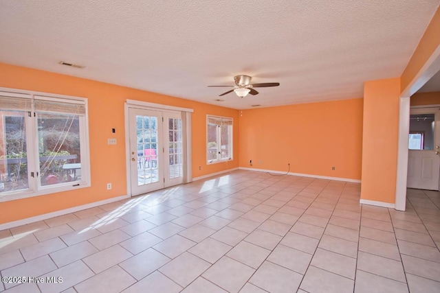 empty room featuring visible vents, baseboards, light tile patterned floors, a textured ceiling, and a ceiling fan