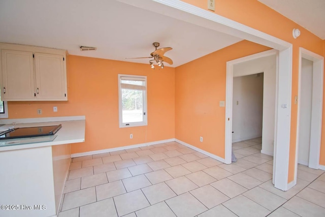 interior space featuring visible vents, baseboards, light countertops, light tile patterned floors, and a ceiling fan