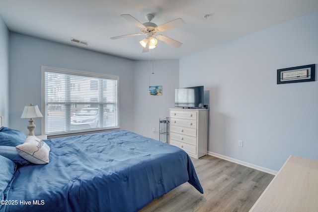 bedroom with baseboards, ceiling fan, visible vents, and light wood-style floors