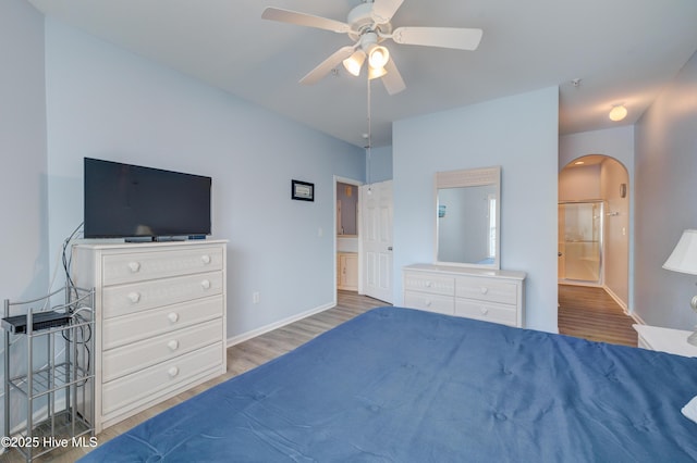 bedroom with arched walkways, wood finished floors, a ceiling fan, and baseboards