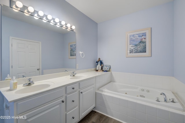 bathroom featuring a whirlpool tub, double vanity, wood finished floors, and a sink